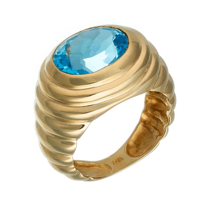 Ring in 14-karätigem Gelbgold. Das Schmuckstück ist mit zwei Dritteln godronierter Ringschiene, die sich schauseitig wölbt und einen blauen Topas in Ovalschliff fasst 