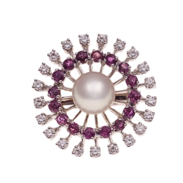 Perlkettenverkürzer in 585  Weißgold. An filgranen Stäben sind Rubine im inneren Kreis und Brillanten im äußeren Kreis in Krabbenfassungen befestigt. Mit Zuchtperle im Mittelpunkt. Hier: Vorderansicht