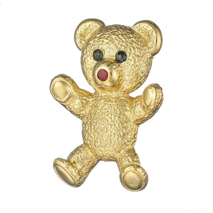Brosche in Form eines Teddybären. 
Der Korpus ist gemustert und stellt damit das Fell des Bärens dar. 
Die Tatzen sind hochglanzpoliert.
Ein Rubin ziert die Nase. Die Augen sind mit Saphiren besetzt. 