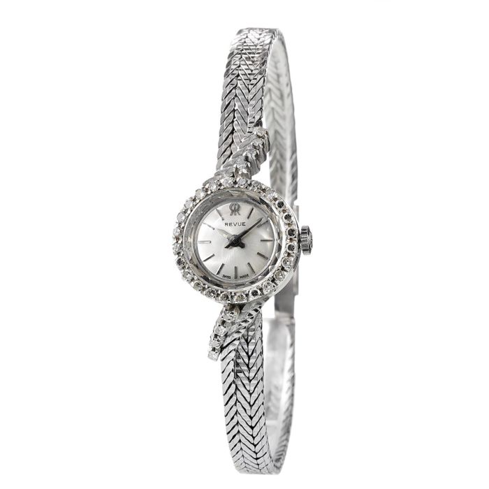 Damen-Armbanduhr von Revue um 1960. Runde Lünette besetzt mit 24 Diamanten in Achtkantschliff je ca. 0,01 ct. und angelötetem schmalen Schmuckband in Fuchsschwanzgliederung sowie diamantbesetztem Bandansatz als Übergang zum Gehäuse mit insges. 8 Diamanten