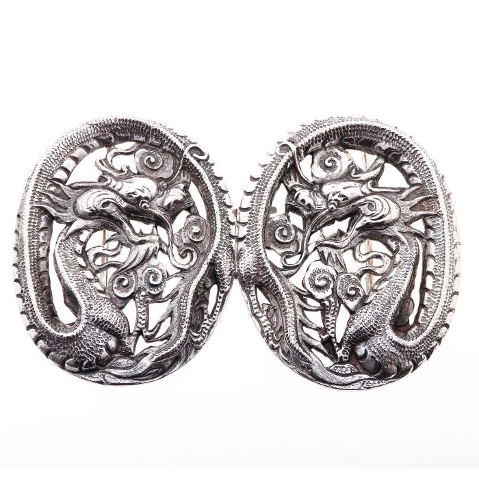 Chinesische Gürtelschnalle in 925er Silber. Ein Drachen ziert das Schmuckstück. Der Schwanz des Tieres bildet die ovalen Formen, indem er sich komplett um den Kopf und die phantasievollen Ornamente wickelt. 