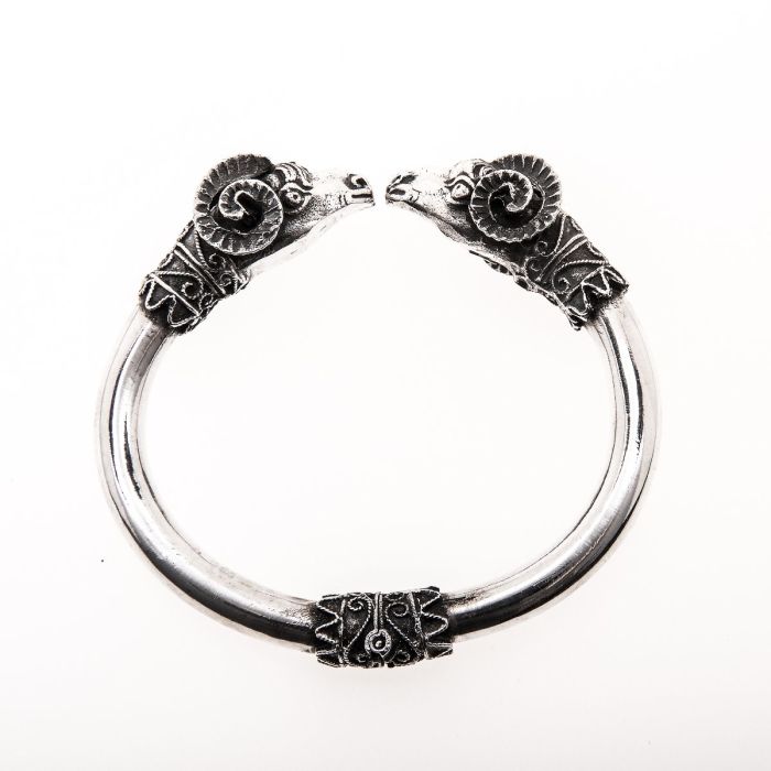 Spangenarmreif. Schauseitig werfen sich 2 Widder kämpferische Blicke zu. Sehr detailgetreu gearbeitete Figuren mit geschwungenen Elementen auslaufend zum schlichten Reif. Zwischen den Köpfen ist der Armreif offen. 