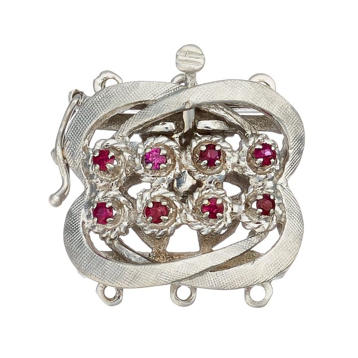 Perlkettenverschluss in 14-karätigem Weißgold. Das Schmuckstück mit seinen geschwungenen Rahmen ist mittig besetzt mit insgesamt 8 Rubinen in blütenartigen Fassungen. 