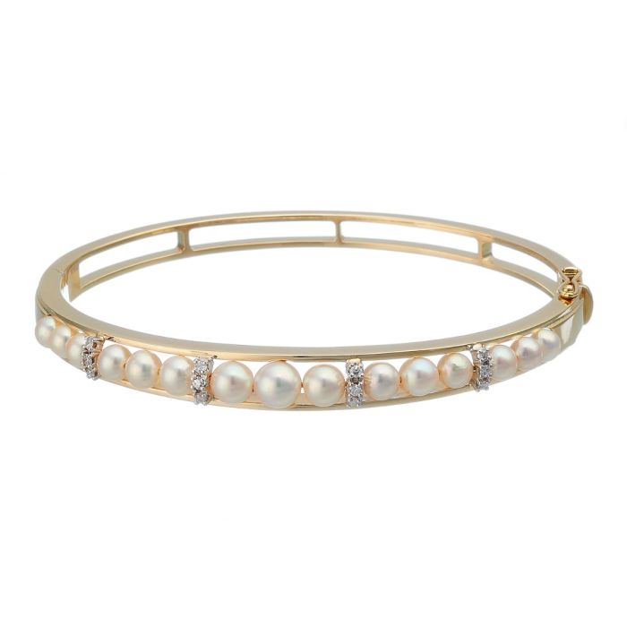 Armreif in 14-karätigem Gold. Schauseitig zieren insgesamt 15 Zuchtperlen den Armreif. Als Zwischenelemente dienen weißgoldene Krappenfassungen mit Diamanten.