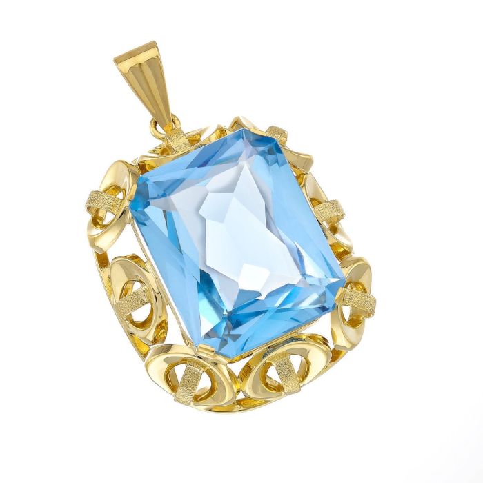 Anhänger in 14-karätigem Gelbgold. Eine achteckige, blau leuchtende, facettierte Aquamarin-Imitation wurde in eine Ornamentverzierung gefasst.
Mit Krappenfassung.