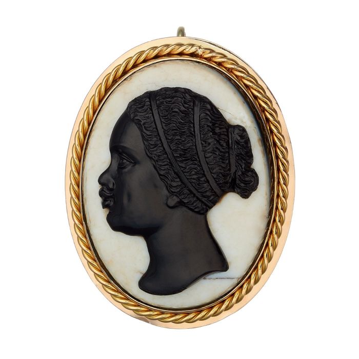 Brosche bzw. Anhänger aus 14-karätigem Gelbgold.
Das ovale Schmuckstück hat einen goldenen Rahmen. Es fasst einen Lagenstein, den eine plastische Frauenbüste schmückt. 