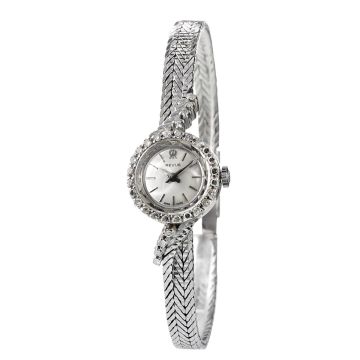 Damen-Armbanduhr von Revue um 1960. Runde Lünette besetzt mit 24 Diamanten in Achtkantschliff je ca. 0,01 ct. und angelötetem schmalen Schmuckband in Fuchsschwanzgliederung sowie diamantbesetztem Bandansatz als Übergang zum Gehäuse mit insges. 8 Diamanten