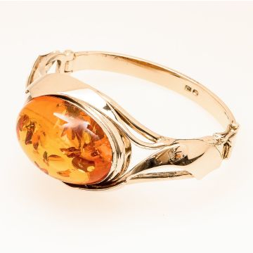 Handgefertigter Armreif in vergoldetem Silber. Mittig hat das Schmuckstück einen großen Bernstein gefasst. 