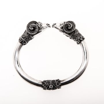 Spangenarmreif. Schauseitig werfen sich 2 Widder kämpferische Blicke zu. Sehr detailgetreu gearbeitete Figuren mit geschwungenen Elementen auslaufend zum schlichten Reif. Zwischen den Köpfen ist der Armreif offen. 