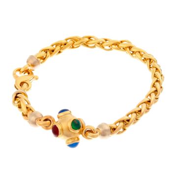Armband in 18-karätigem Gold. 
Die Zopfgliederung des Bandes hat  ein kugelartiges Zwischenelement, das mit jeweils 2 Rubin-, Smaragd-, und Saphir-Imitationen besetzt ist. Die angedeuteten Halterungen sind in Weißgold gearbeitet.