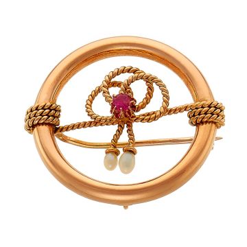 Jugendstil-Brosche in 14-karätigem Rotgold. In Form eines halbrund gewölbten offenen Reifens umwickelt mit Filigrandraht mittig zur Schleife gebunden und mit einem Rubin und zwei Saatperlen.