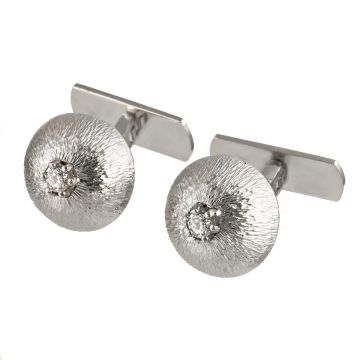 Manschettenknöpfe in 18-karätigem Weißgold mit jeweils einem funkelnden Brillanten in Krappenfassung auf der runden, gewölbten, ziselierten Form der Schauseite. 