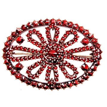 Antike Granatbrosche aus vergoldetem Silber. In der schlichten ovalen Form der Brosche mit aneinandergereihten  schlaufenförmigen Ornamenten mit einem mittig größeren Granat. 
Die Steine sind in Krappenfassungen. 
