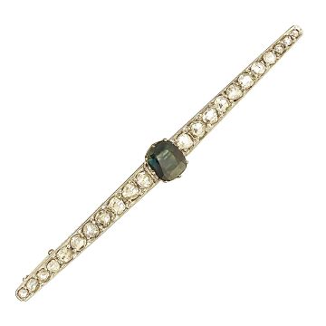 Klassisch elegante Stabnadel des Art-Déco, in schmaler langgezogener Rautenform, mittig besetzt mit einem Saphir in Ovalschliff in krönchenartiger Krappenfassung. Flankiert von Diamantrosen, im Verlauf gefasst in Weißgold mit ziseliertem Rand, auf einem g