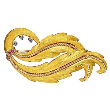 Klassische Brosche in Form von phantasievoll geschwungenen Blättern. Filigran gearbeitete weißgoldene Elemente verlaufen ebenfalls geschwungen entlang der Blätter. Die gelbgoldenen Flächen sind satiniert. Kleine Rubine und Saphire am unteren Teil zieren d